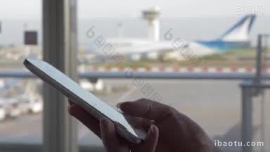 一个女人在机场候机楼窗口用智能手机打短信的特写镜头